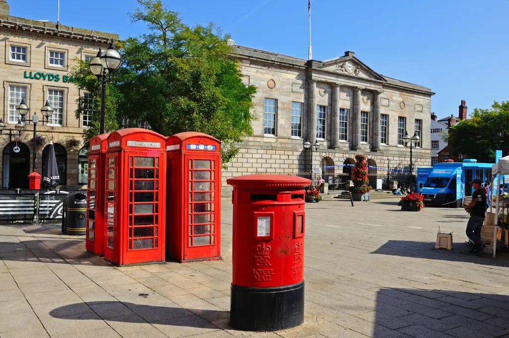 Four red telephone boxes and a red postbox outside of a city hall in Stafford.